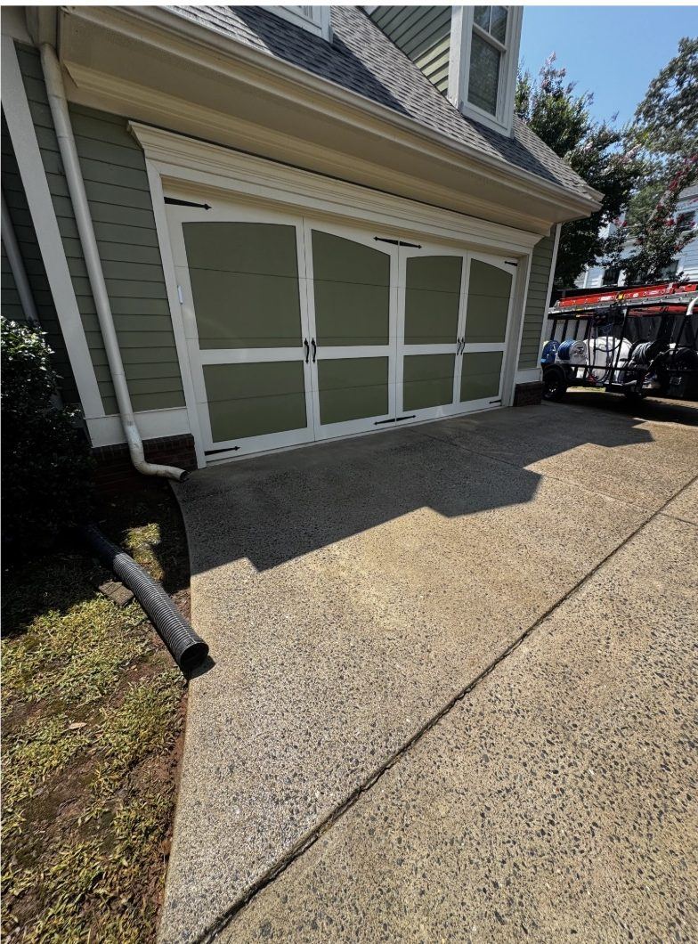 The same garage apron after surface cleaning, the concrete an even light gray with the algae gone
