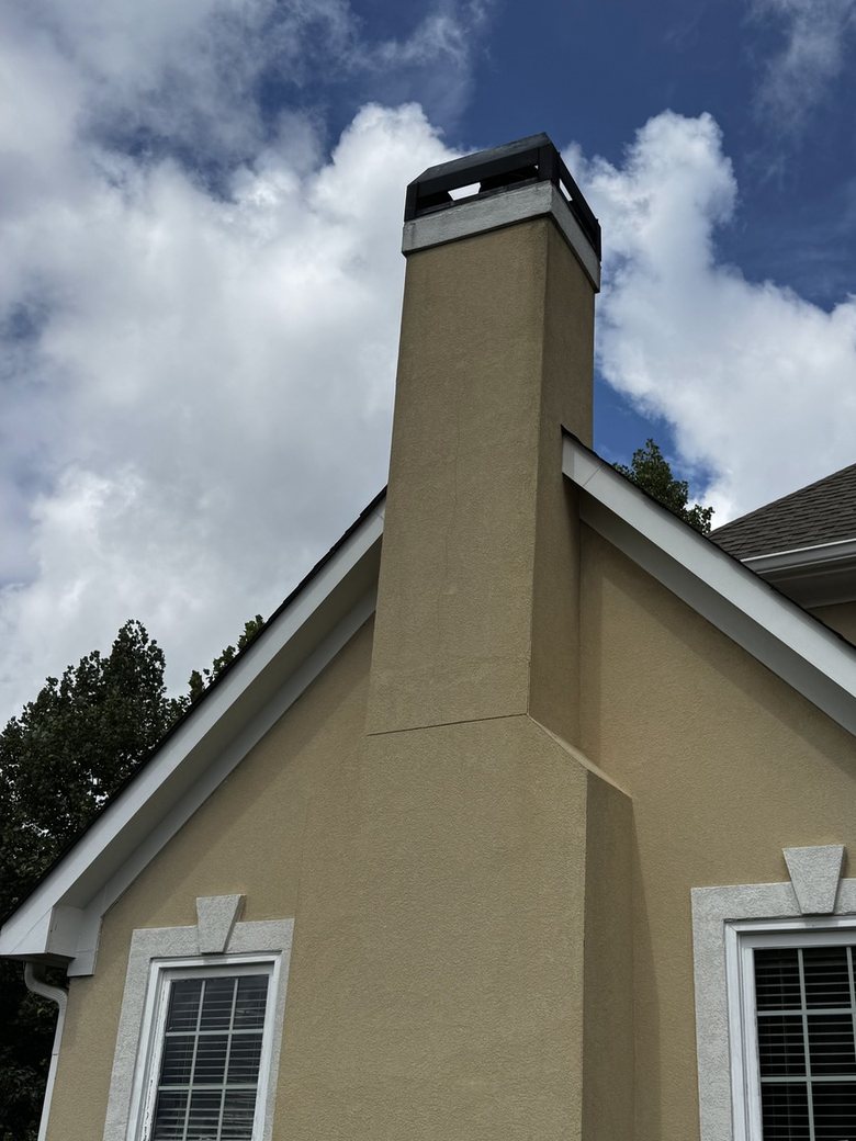 The same stucco chimney after a low-pressure soft wash, the streaking gone and the stucco back to an even tan